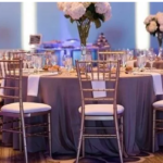 A beautifully set event with gold Chiavari chairs arranged around elegant tables.