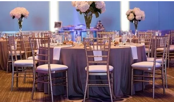 A beautifully set event with gold Chiavari chairs arranged around elegant tables.