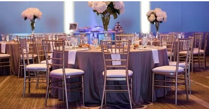 A beautifully set event with gold Chiavari chairs arranged around elegant tables.